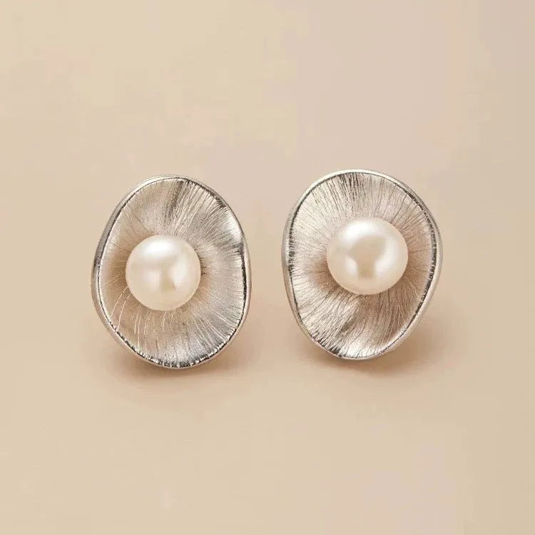 A pair of gold-coloured geometric sterling silver stud earrings with white pearl accents on a white background.