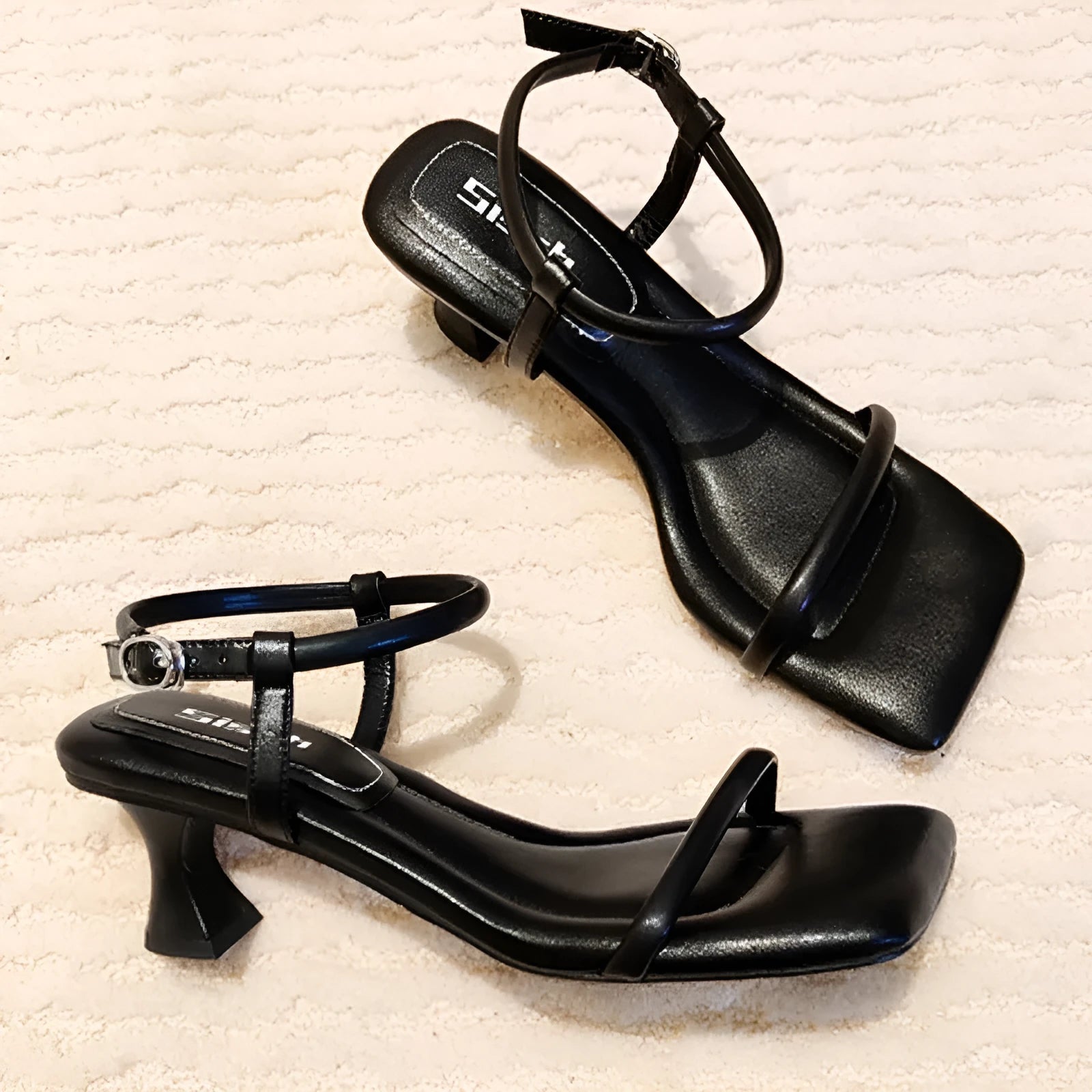 Black women's high heel sandals with a single ankle strap, square toe, and thick heel.