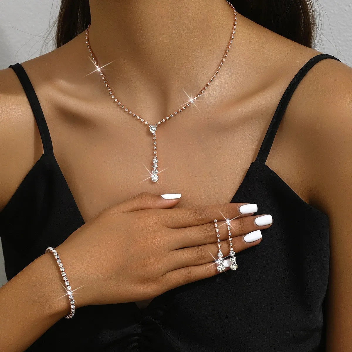 Women's silver pink rhinestone heart tassel earrings, necklace, and bracelet jewellery set on a white background.