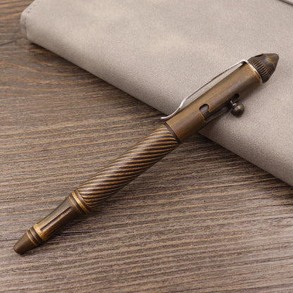 Brass tactical pen with press bolt mechanism showing cylindrical design and six ring details