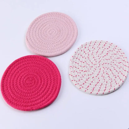 Set of three round grey cotton cord coasters, each 18cm in diameter, on a wooden table.