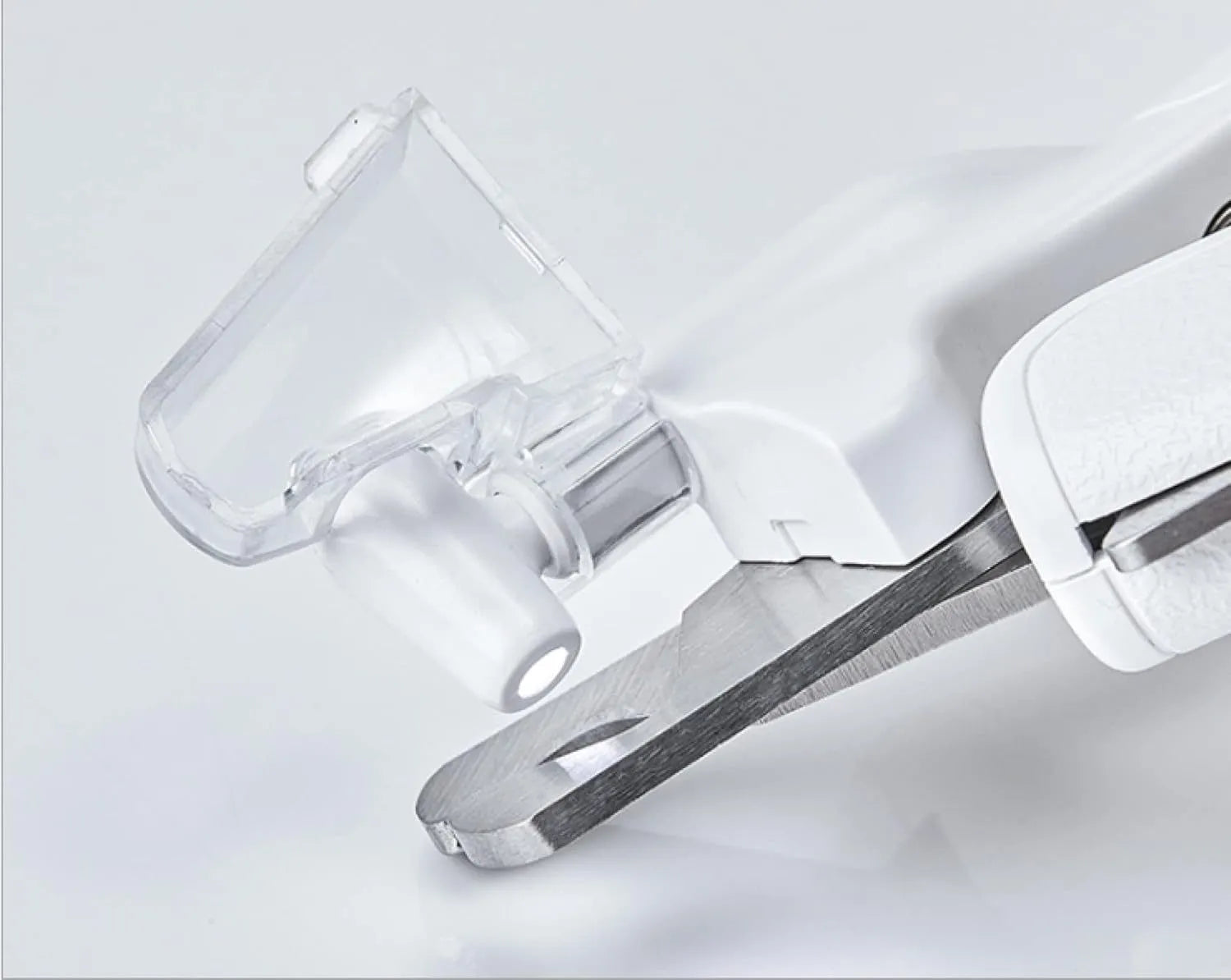 White pet nail clippers with LED light, anti-splash guard, and built-in nail file on a flat surface.