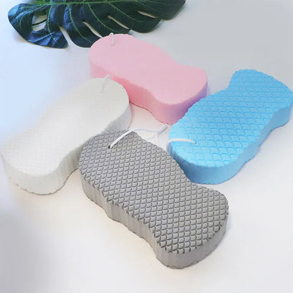White 3D bath ball sponge with a fish scale exfoliating texture on a blue background.