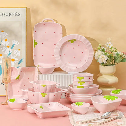 Porcelain dinnerware set with strawberry pattern, showing plates, bowls, and a twist spoon in various sizes