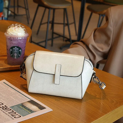 Women's brown shell-shaped genuine leather messenger bag with a single shoulder strap and visible stitching.