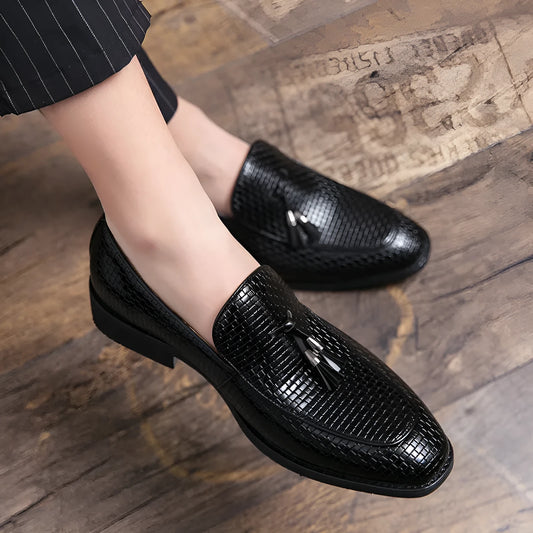 Men's black pointed toe slip on shoe with a decorative tassel on the artificial PU upper.