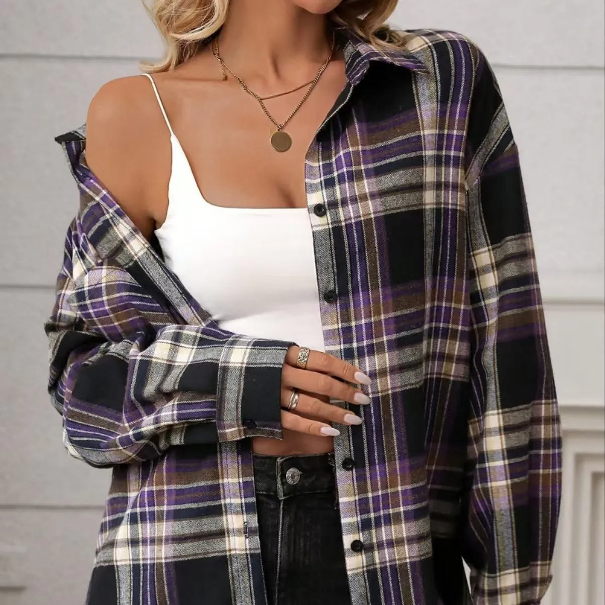 A woman modelling a loose-fit black, green, and purple plaid shirt with long sleeves.
