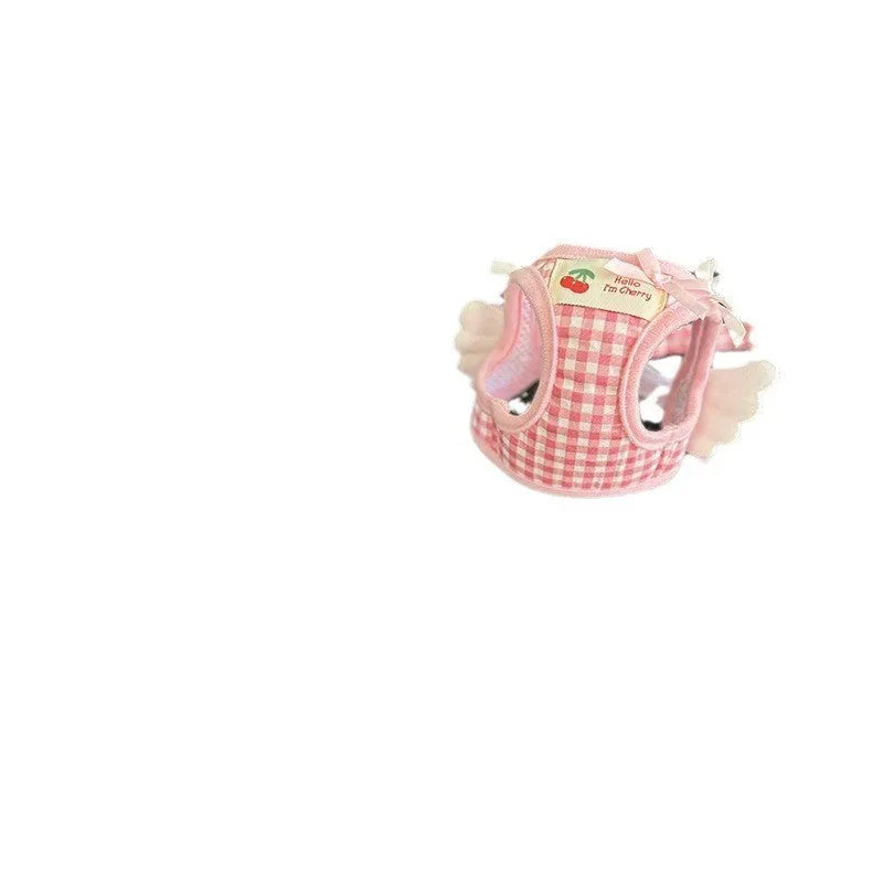 Small dog wearing adjustable cotton harness in pink with chest-back design and hand holding rope attachment