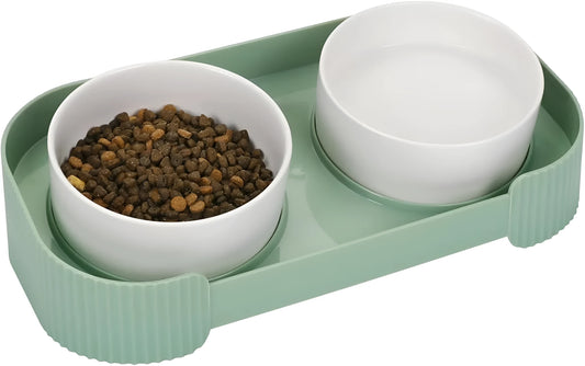 Green ceramic raised cat feeder with two tilted bowls on a non-slip white stand.
