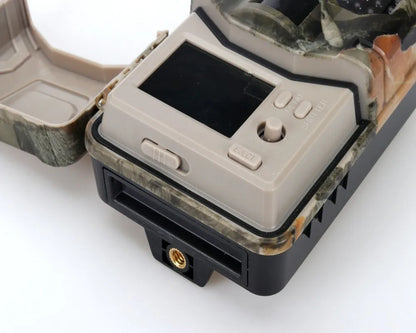 Camouflage infrared hunting trail camera with lens and infrared LEDs, shown with mobile phone displaying APP control interface.