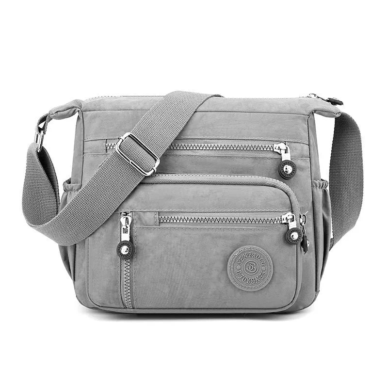 Soft grey nylon messenger bag with a single shoulder strap, shown in a square vertical shape.