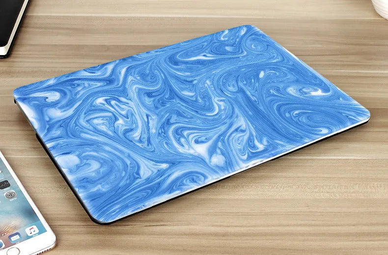 Plastic MacBook protective case in a marble pattern colour, shown next to a compatible Apple laptop.