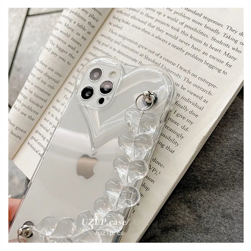 Transparent TPU iPhone case with love bracelet and heart chain design on a table.