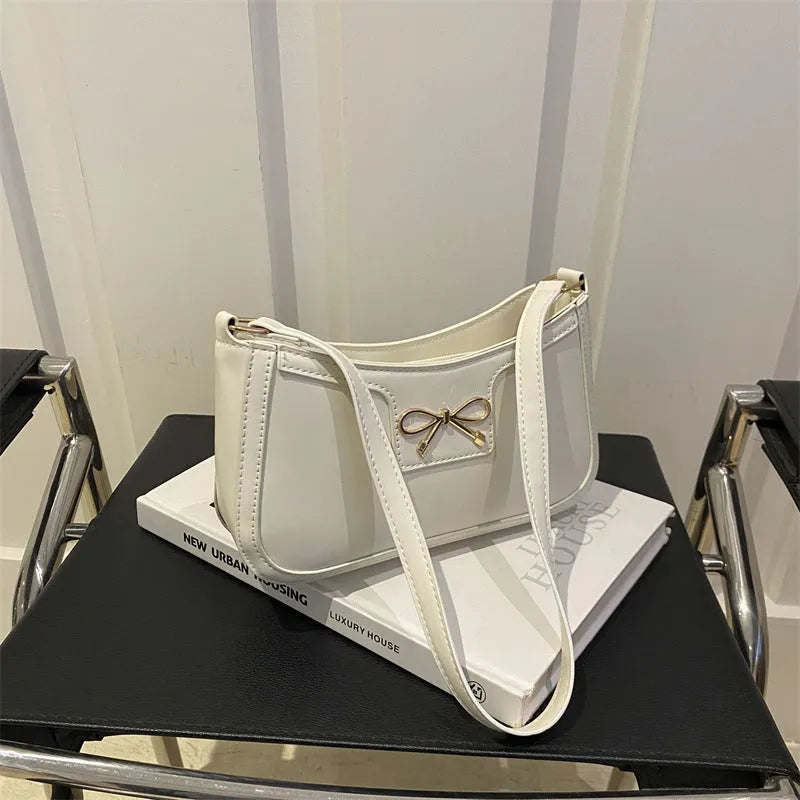 Western style shoulder bag with bow detail in rose pink colour, showing horizontal square shape and single strap.