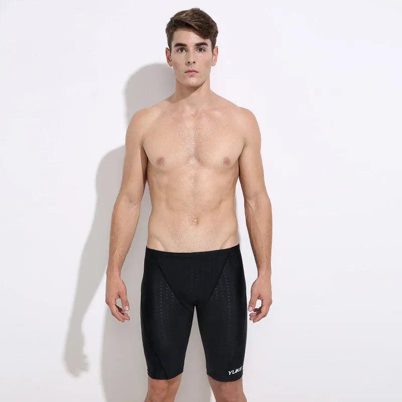 Men's black swimming trunks, goggles, and cap set laid out with ear plugs and carry bag
