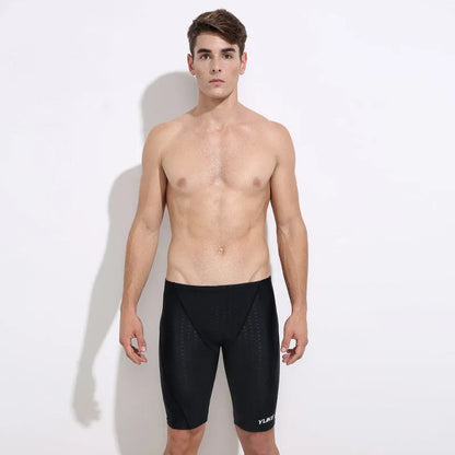 Men's black swimming trunks, goggles, and cap set laid out with ear plugs and carry bag