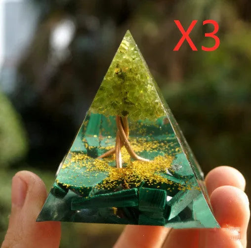 A small 6cm clear epoxy resin pyramid ornament containing pieces of natural crystal gravel on a flat surface.