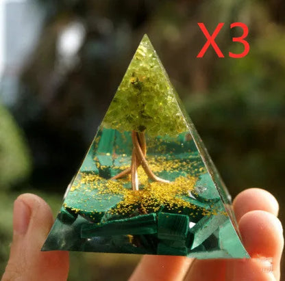 A small 6cm clear epoxy resin pyramid ornament containing pieces of natural crystal gravel on a flat surface.