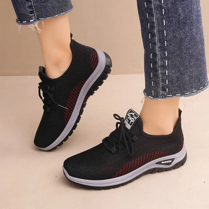 Women's low-top sneakers in black with a cross strap detail on the artificial PU and mesh upper.