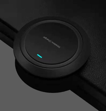 Round white wireless charging pad on desk next to mobile phone