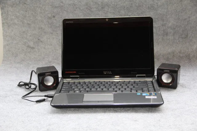 Black square USB computer speaker measuring 10cm with matte finish beside monitor
