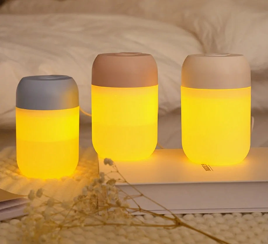 White cylindrical humidifier with USB cable on a desk, showing compact 15cm height and aromatherapy function for essential oils.