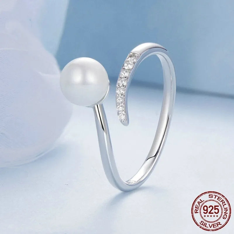 Silver adjustable open ring with white shell pearls on a white background.