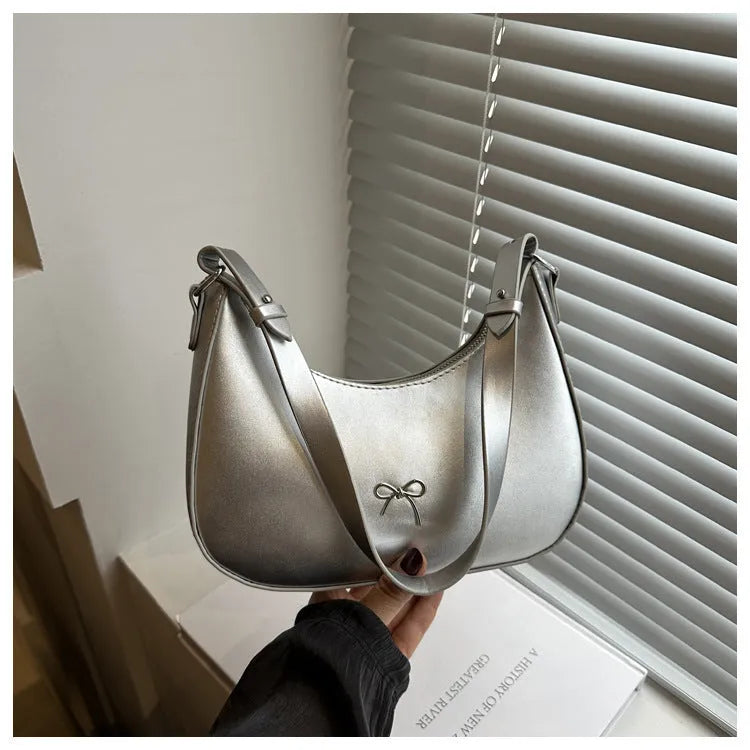Women's silver dumpling-shaped PU crossbody bag showing front sandwich pocket and single shoulder strap.
