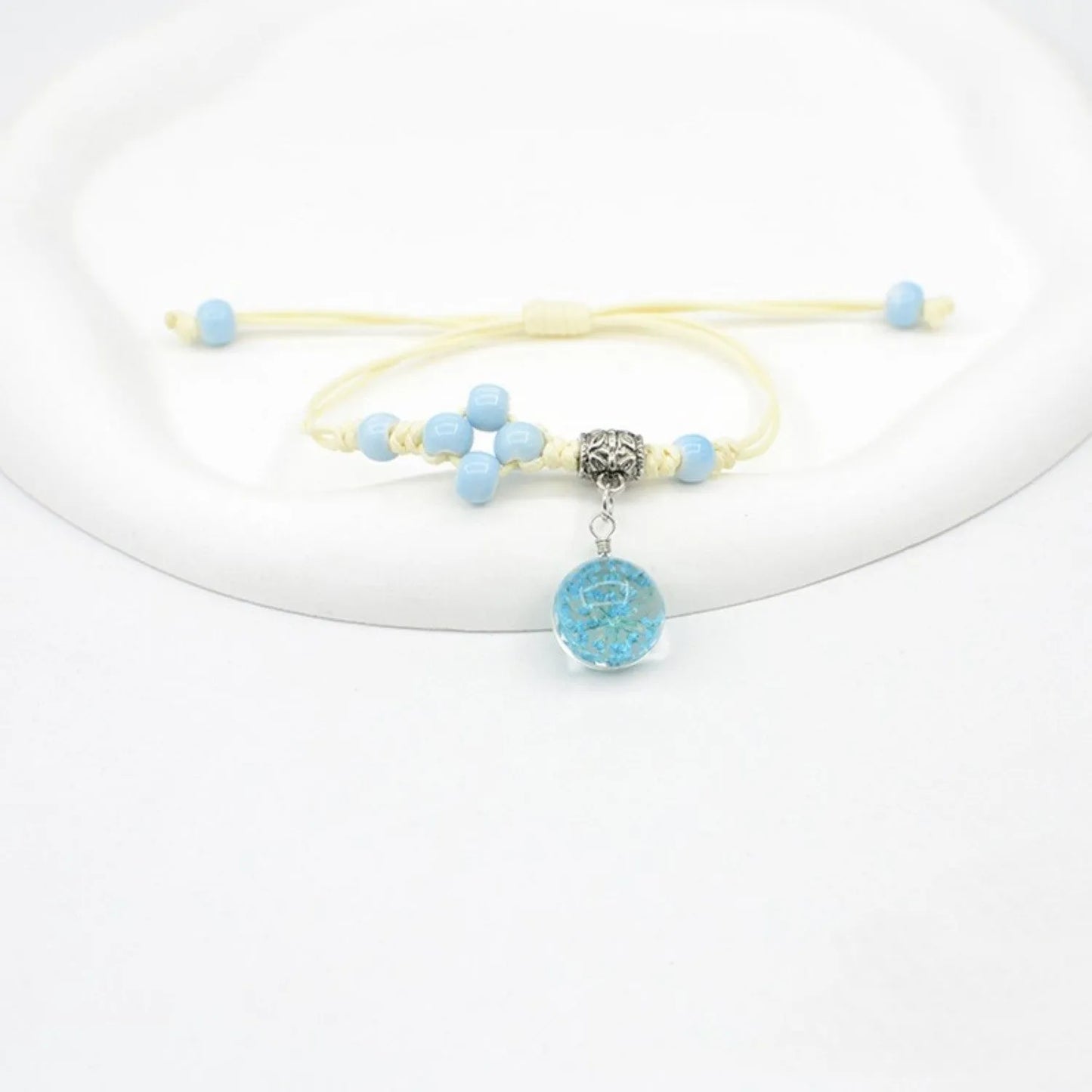 Hand-woven glass bracelet with large 1.4 cm beads containing real dried flowers, shown in blue.