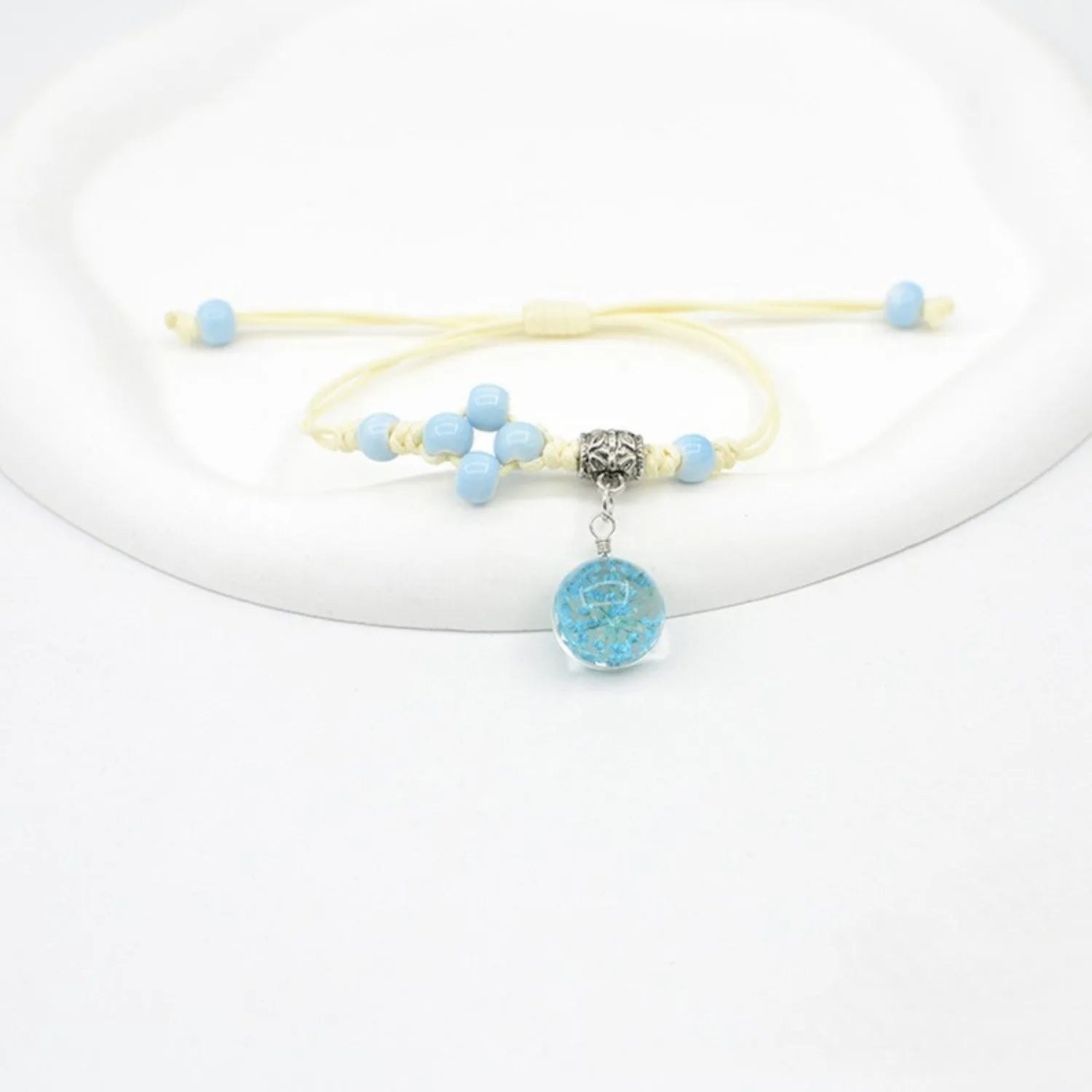Hand-woven glass bracelet with large 1.4 cm beads containing real dried flowers, shown in blue.