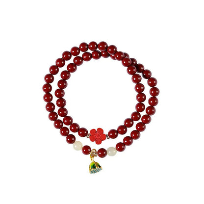 Close-up of a hand-woven purple gold cinnabar bead bracelet with a lotus seedpod charm.
