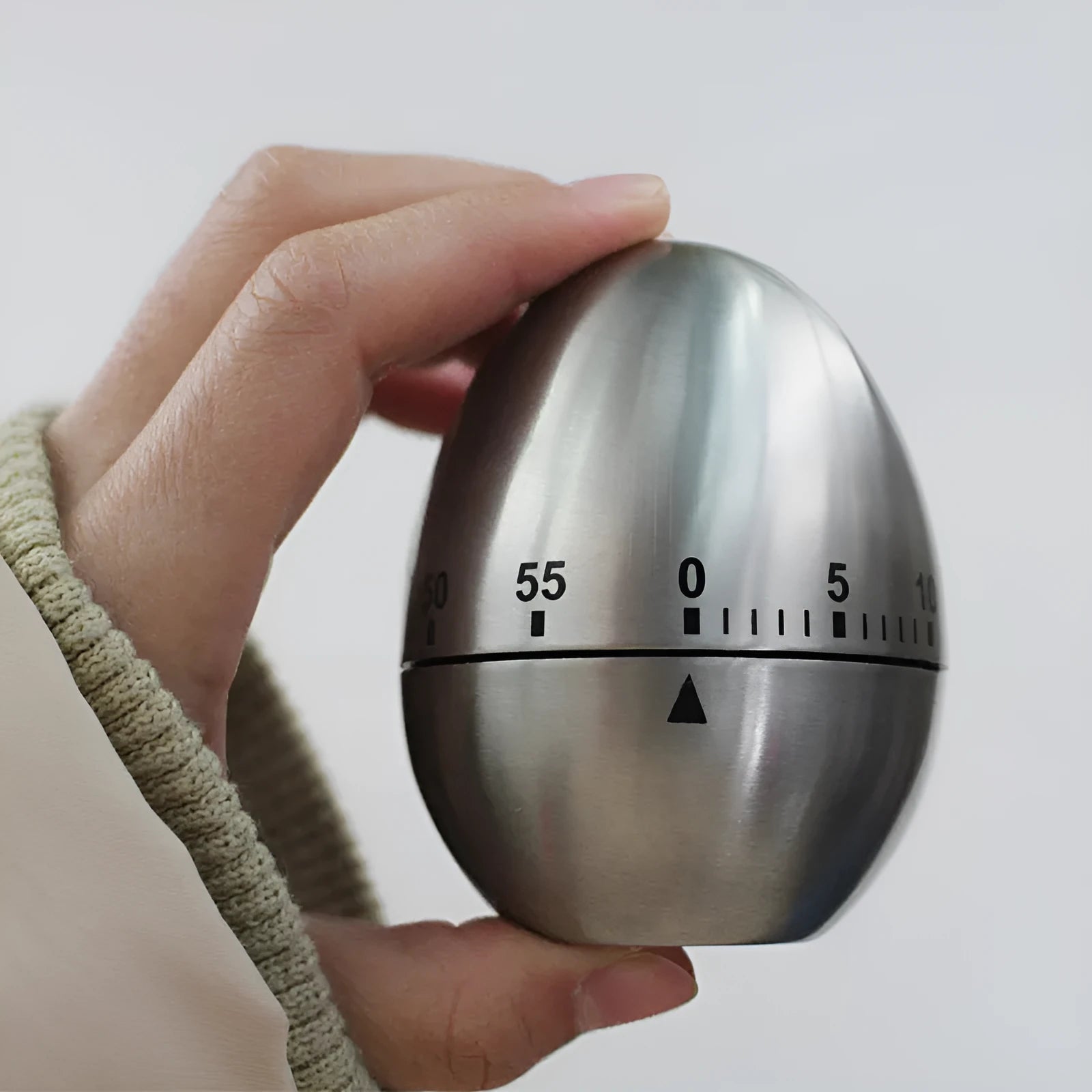 Stainless steel mechanical kitchen timer with egg-shaped design on kitchen counter