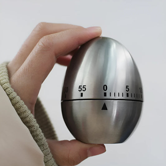 Stainless steel mechanical kitchen timer with egg-shaped design on kitchen counter