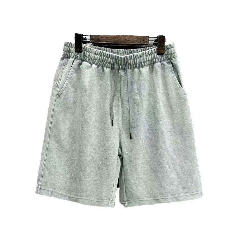 Men's distressed light blue cotton shorts with a loose straight-leg casual fit on a neutral background