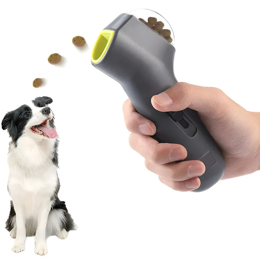 Grey plastic pet snack catapult launcher toy with ergonomic handle, shown with treats.