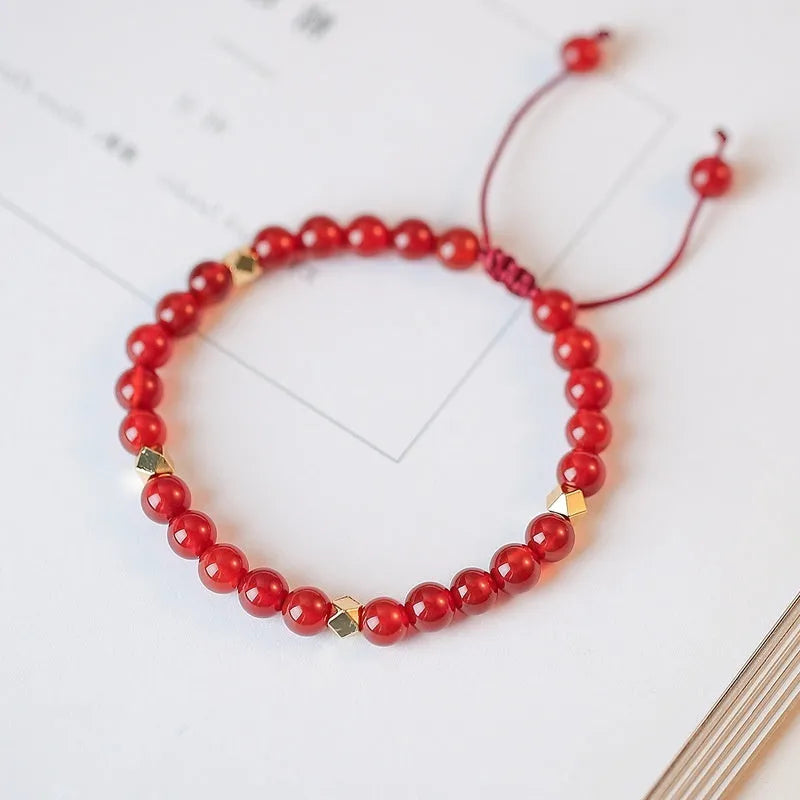 Hand-woven red agate beads bracelet with lucky charm in ethnic style, showing diamond-shaped beads.