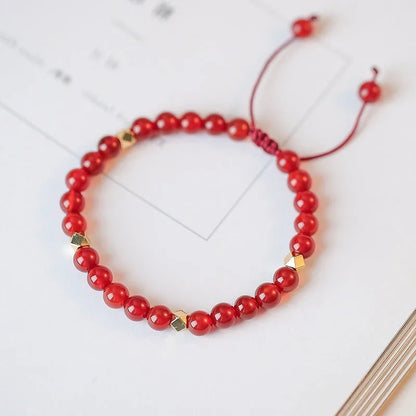 Hand-woven red agate beads bracelet with lucky charm in ethnic style, showing diamond-shaped beads.