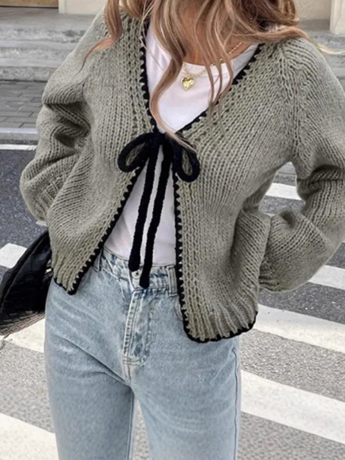 Loose grey lace-up front cardigan sweater with crocheted flower detail on a model.