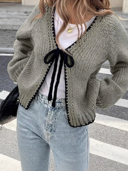 Loose grey lace-up front cardigan sweater with crocheted flower detail on a model.