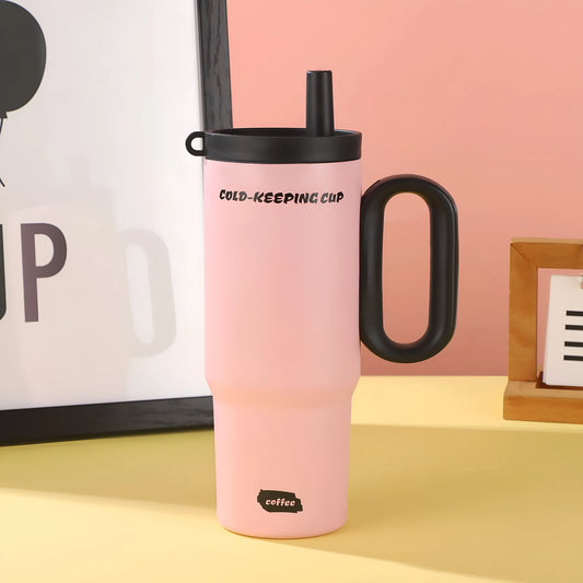 Large pink insulated straw cup with a black handle and push-button lid on a wooden table