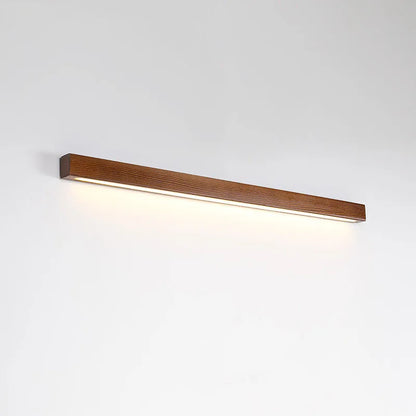 Walnut-coloured minimalist wooden strip wall lamp with integrated LEDs, mounted on a plain wall.