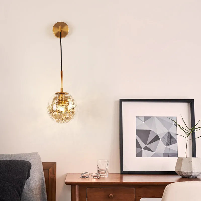 Glass wall lamp with golden flower finish and 15cm diameter, mounted beside bed with LED illumination