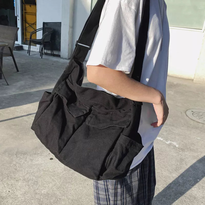 Canvas messenger bag in black, white, green, and brown with multiple pockets and adjustable strap