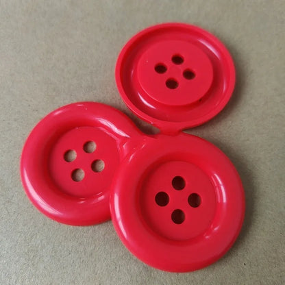 Assorted oversized round plastic buttons in various colours showing four-hole sew-through design.