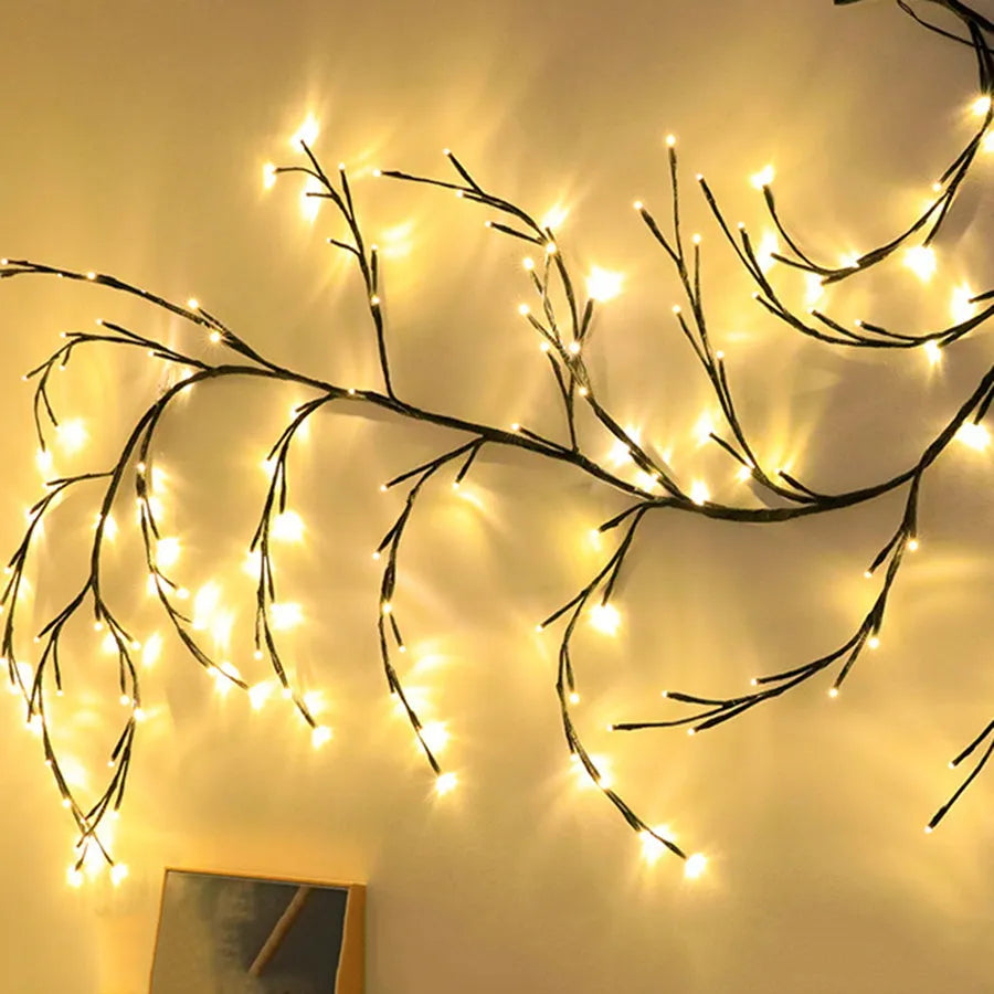 Flexible DIY willow vine LED light garland with warm white lights shaped on a wall.