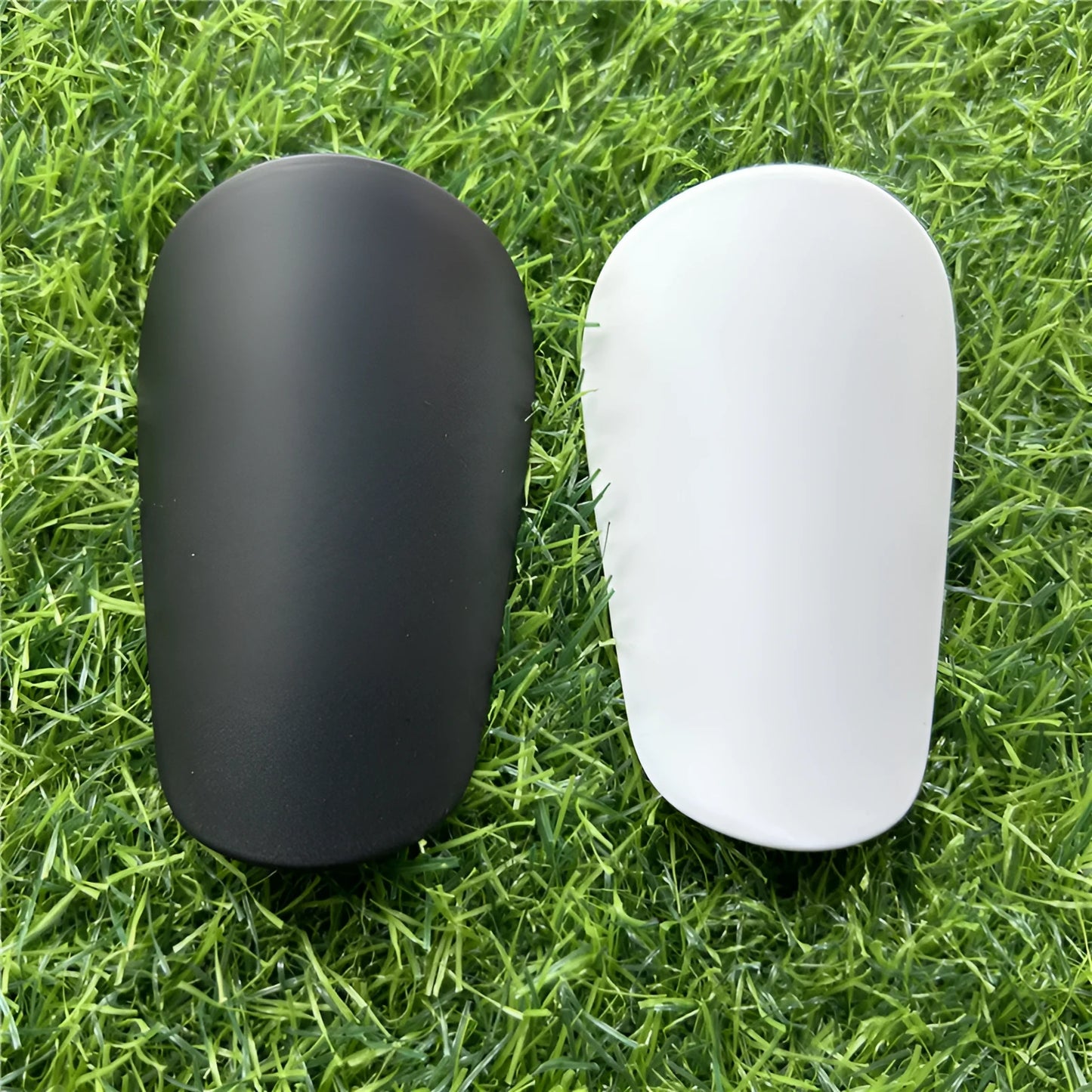 Extra small plastic football shin guards in black and white colours for youth players