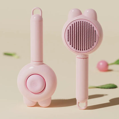 Green self-cleaning pet grooming brush with a release button and rubber-tipped metal pins on a non-slip handle.