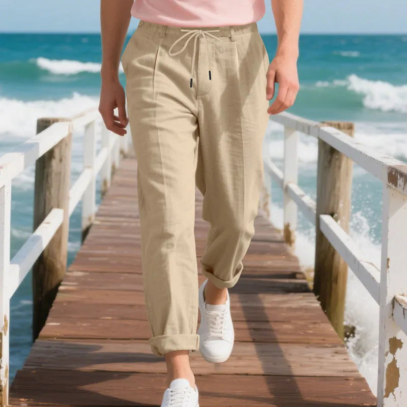 Men's light beige linen trousers with a loose straight leg and drawstring waist on a hanger.