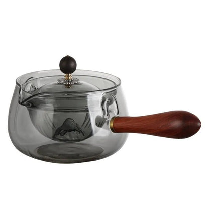 Glass teapot with wooden handle showing transparent borosilicate construction and removable infuser