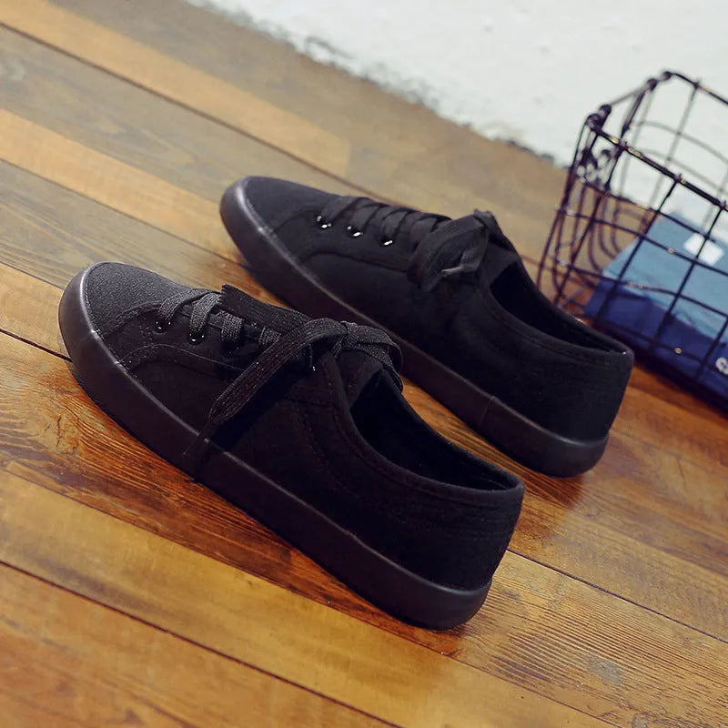All-black women's canvas work shoes with flat rubber soles and lace-up front